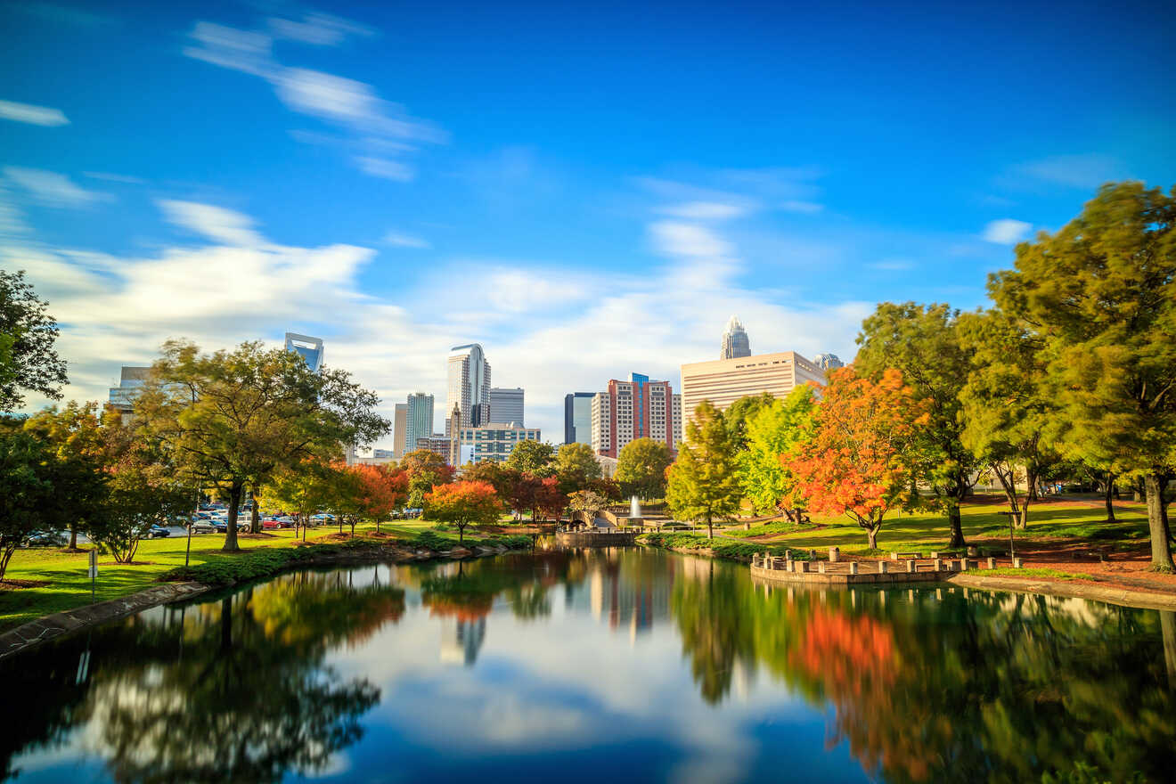 Charlotte's cityscape reflected in a tranquil lake surrounded by trees with autumn foliage